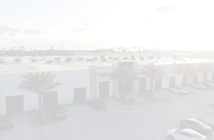 Aerial view of a white building with palm trees and cars in the parking lot.