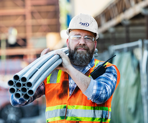 Construction worker carrying conduit.