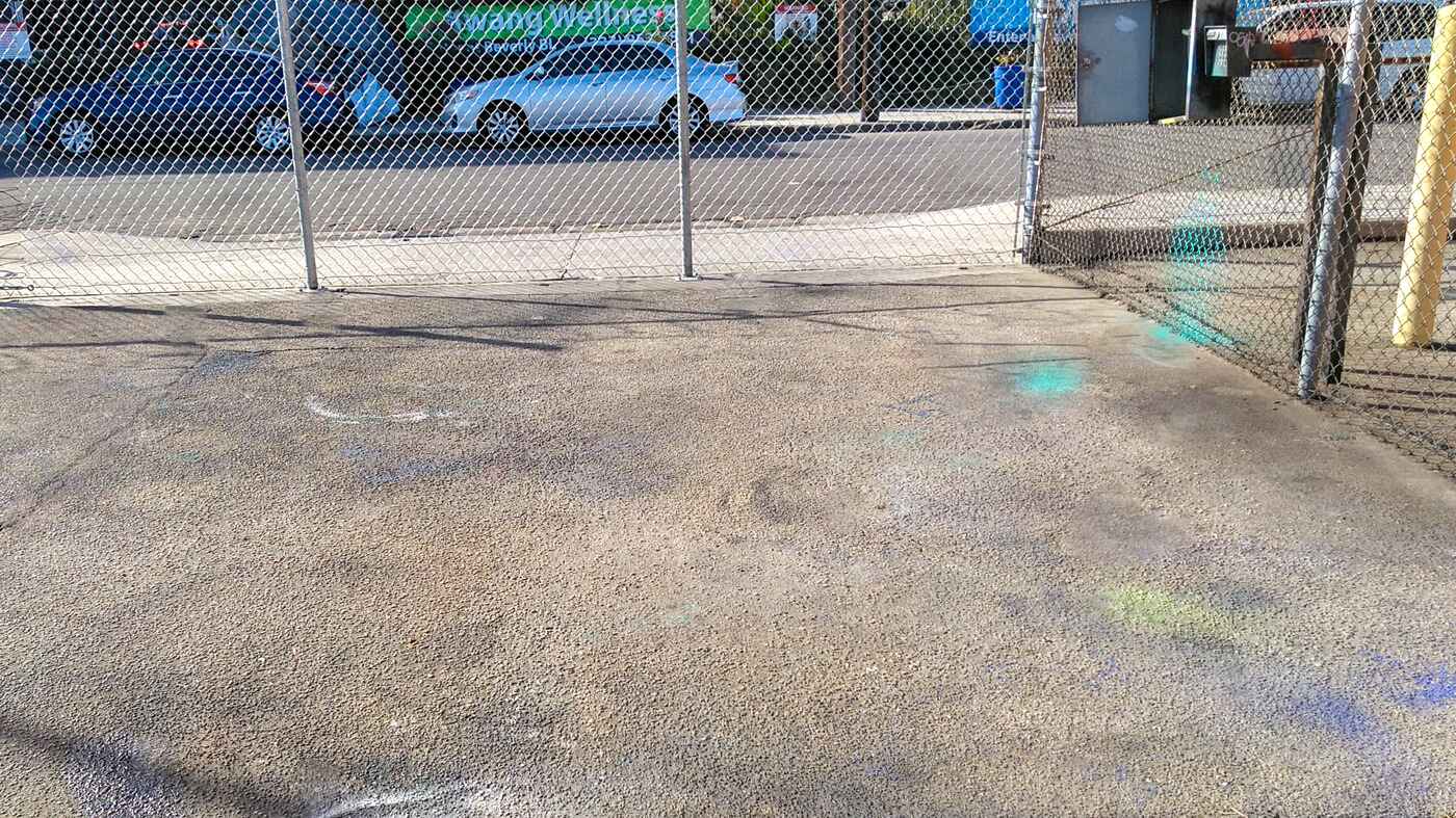 Asphalt lot behind a chain link fence with multicolored markings.