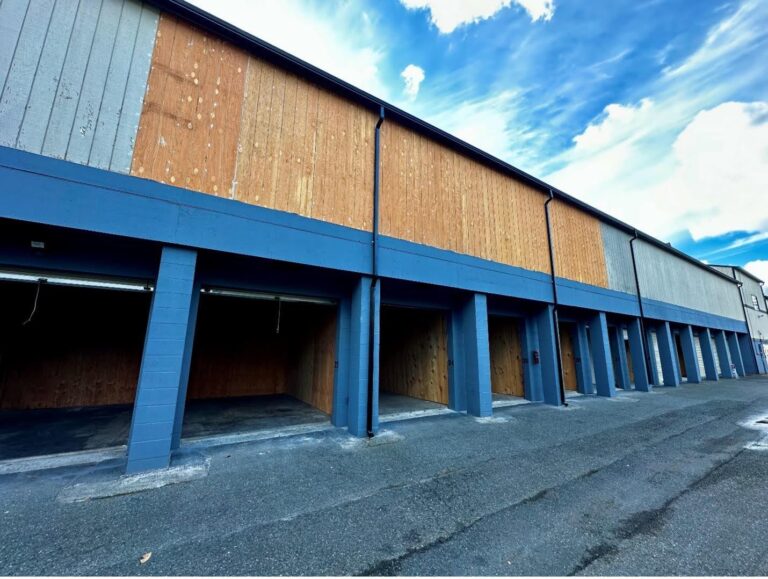 Row of empty garages with plywood covering the upper walls.