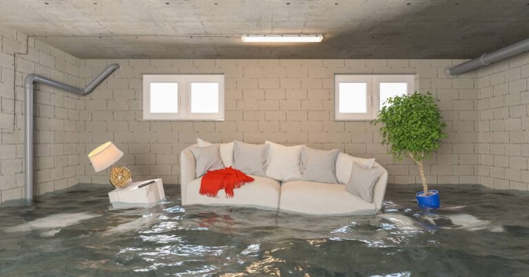 Flooded basement lifting couch, end table with lamp, and potted plant off the floor | ATI Restoration