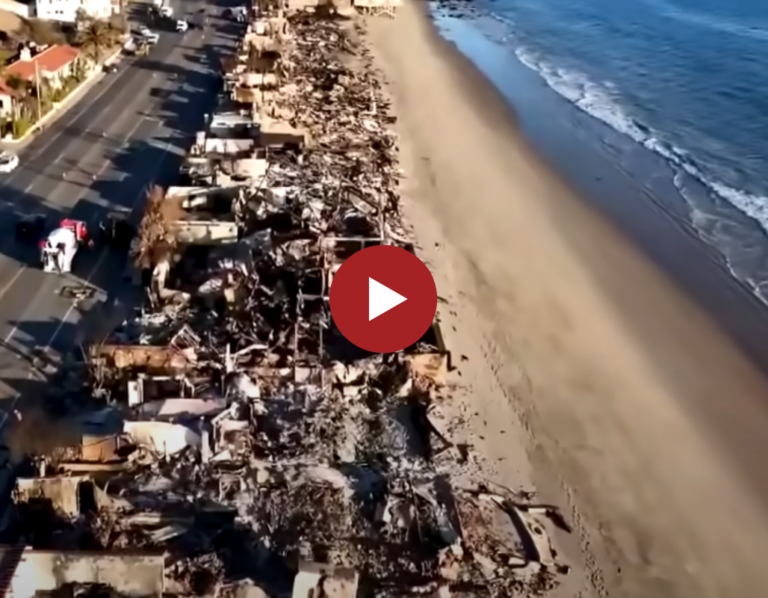 Aerial view of fire-ravaged buildings along a beach next to a road.